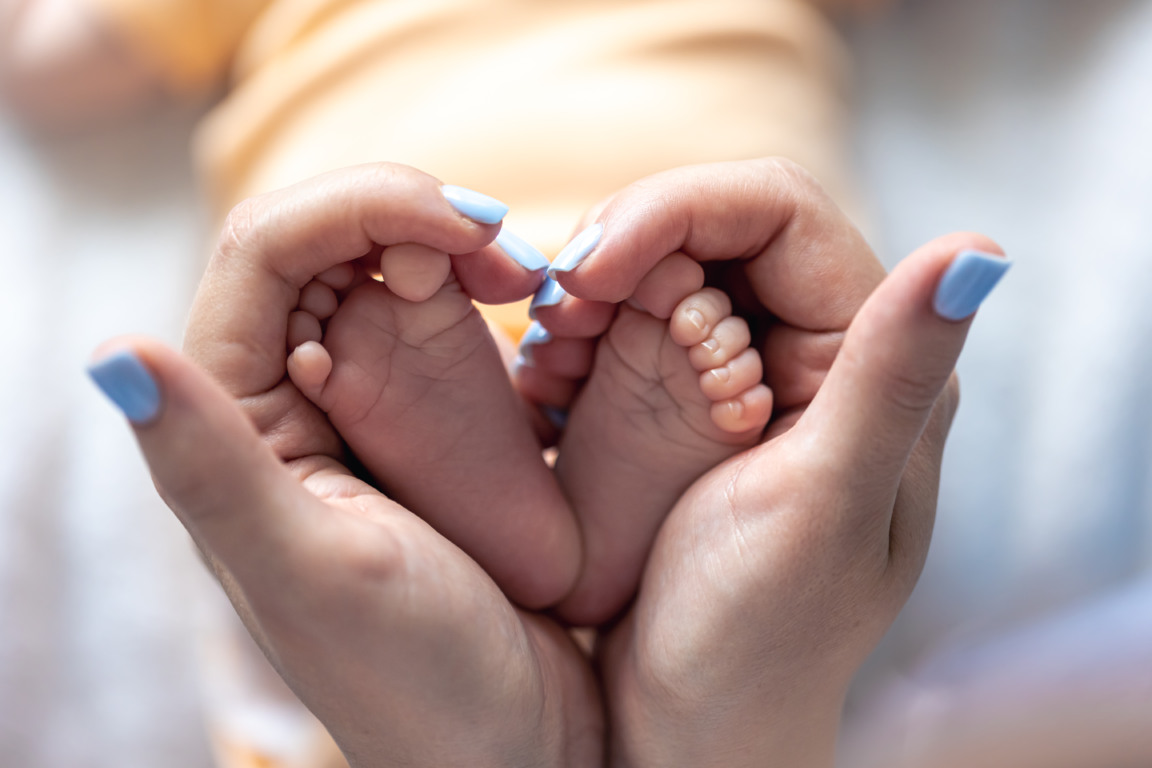 Mom holds the legs of a newborn baby in her hands, close-up, soft focus, concept of motherhood and care. Mom holds the legs of a newborn baby in her hands, close-up, soft focus, concept of motherhood and care.